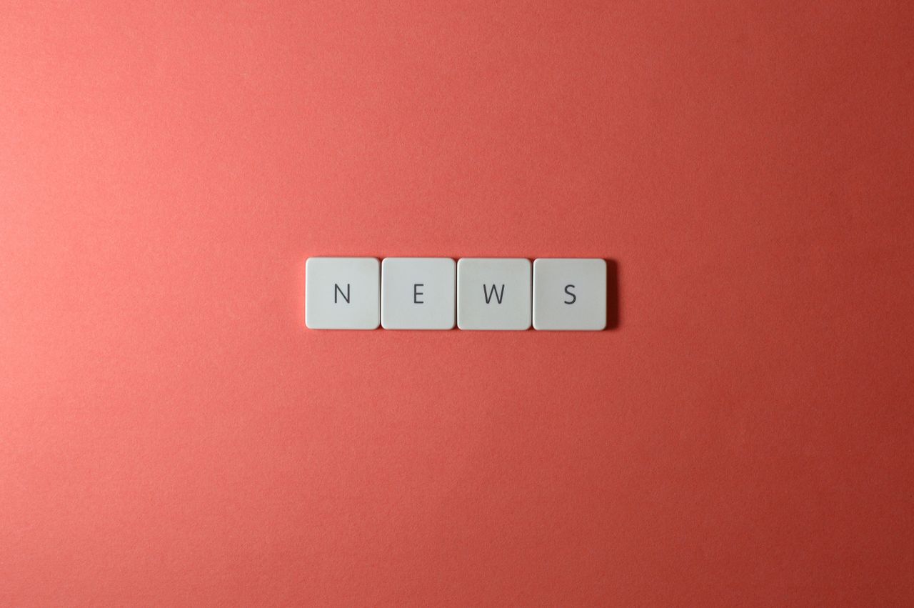 Close-up of keyboard keys spelling 'NEWS' on a red background, minimalist style.